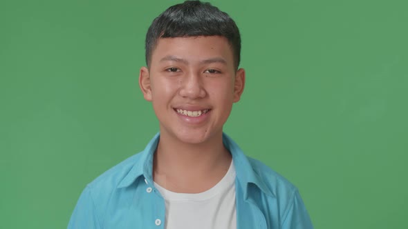 Young Asian Boy Warmly Smiling On Green Screen Background In The Studio