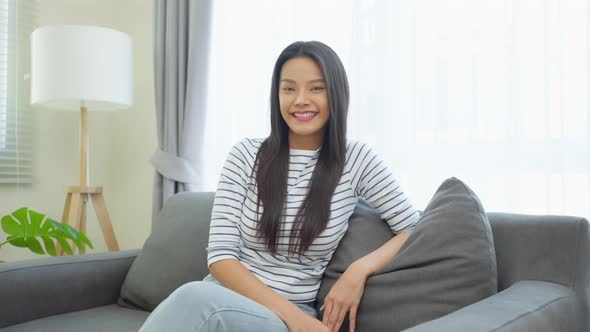 Portrait of Asian beautiful woman sit on sofa in living room at home.