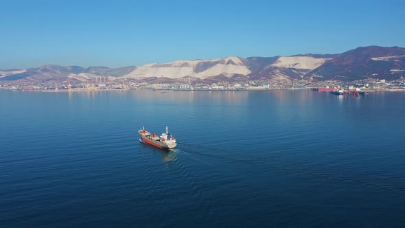 Aerial View of Ultra Large Cargo Ship at Sea Leaves Port at Sunny Day