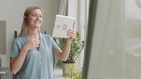 Woman Using Tablet Standing by Window