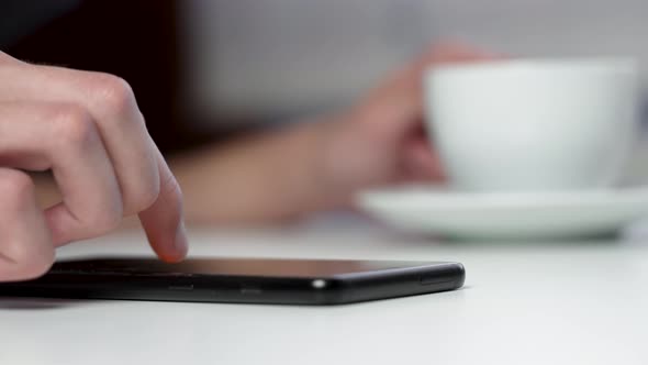 Young businessperson touching the touchscreen of a mobile phone while using a smartphone