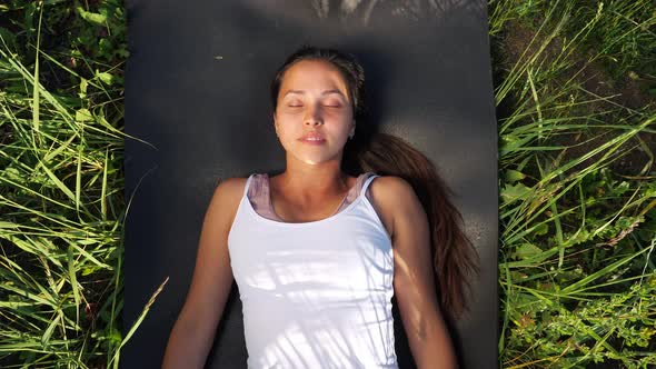 Beautiful Woman Lies on a Gymnastic Mat Among the Grass