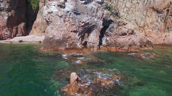 Flight By Drone From a Stone Arch on the Seashore on a Bright Sunny Day