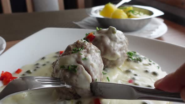 Eating meatballs with white sauce. Traditional German food called Koenigsberger Klopse.