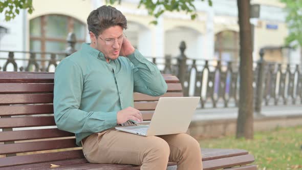 Man having Neck Pain while using Laptop on Bench