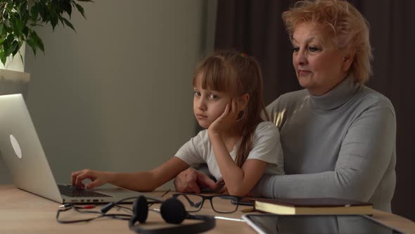 Grandmother and Sad Granddaughter Study Online on a Laptop