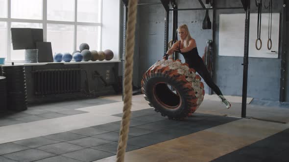 Female Athlete Flipping Tire while Training in Gym alt