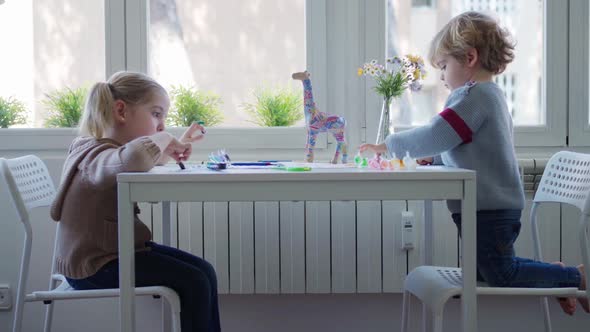 Preschool brother and sister painting together at home