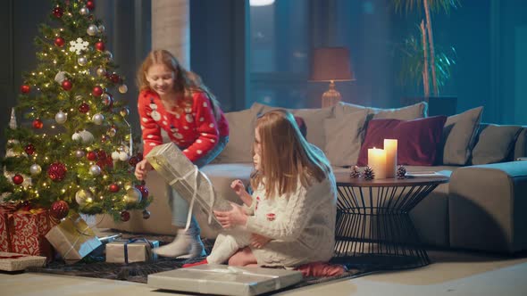 Two Sisters Opening Christmas Presents with Mother at Home