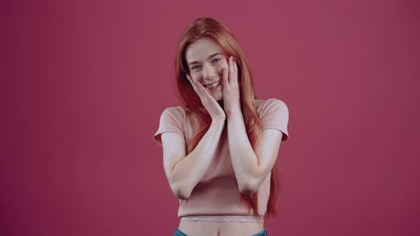 Excited Redhaired Young Woman of 20 Years in a Pink Casual Tshirt Isolated on a Pink Background