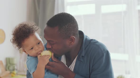 Dad and Infant Son Eating Apple Together