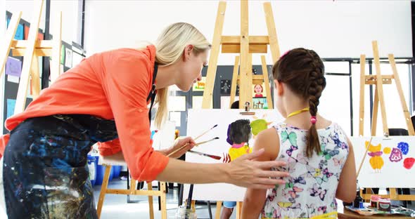 Teacher assisting girl in drawing class