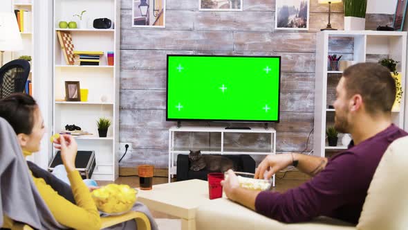 Caucasian Couple Sitting on Chairs Looking at Tv