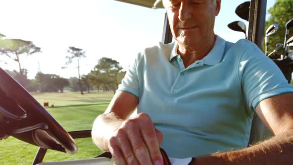 Golfer sitting in golf buggy wearing golf glove