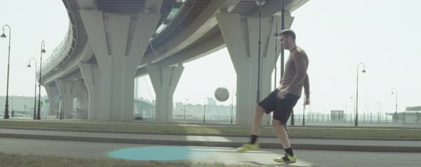 Football Player Juggling Ball on City Street