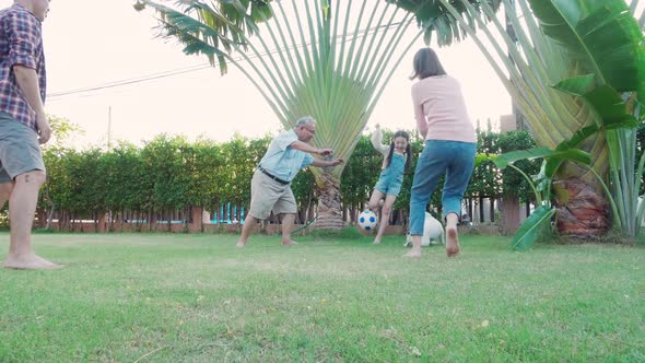 Family Asian parent, Grandfather, and child daughter play soccer together at home