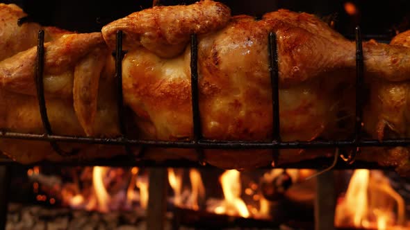 Slow Motion Closeup of a Roasted Chickens on Spit Grilled Over Wood Fire on Big Bbq Barbecue