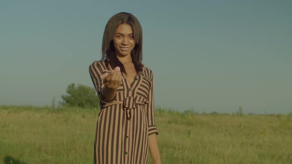 Playful Lovely African Woman Walking on Field and Beckoning at Daybreak