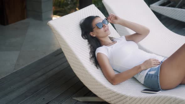 Woman in Sunglasses Lies on Deck Chair Outdoors, Relaxes and Enjoys Vacation