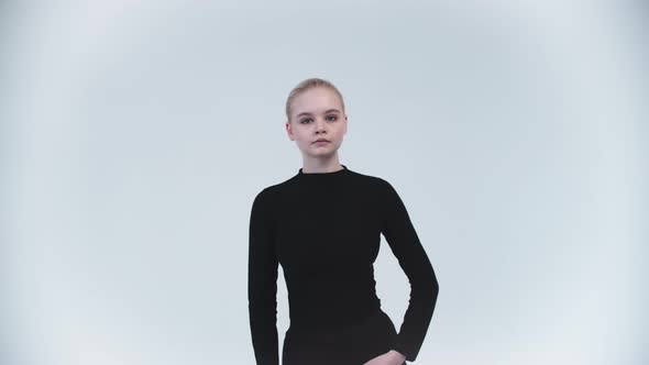 Gymnastics  Young Woman Raising Up Her Leg Against Her Body and Holding It  Looking in the Camera