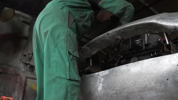 LOCKED OFF LOW ANGLE view of Mechanic checking front body work on car