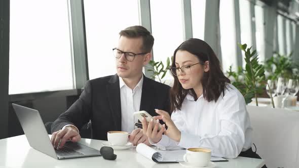 Young Business Lady And Manager Discussing Projects And Ideas Using Smartphone And Laptop Over Cup