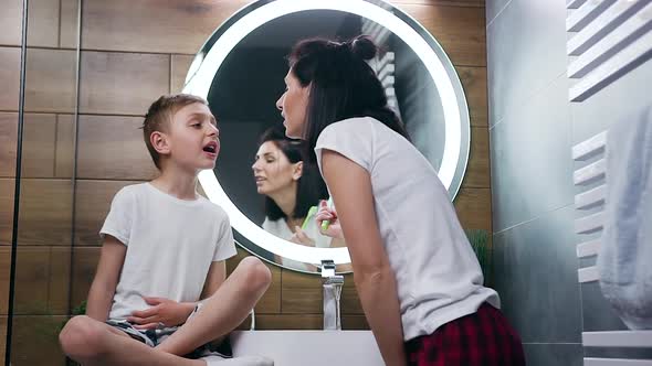 Brunette Which Cleaning Son's Teeth Using Toothbrush and After that Kissing Him to Nose