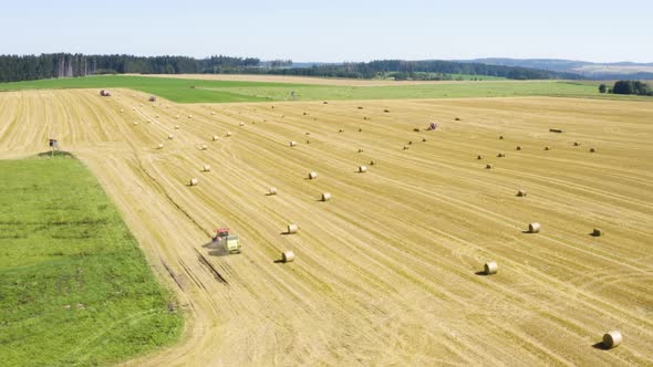 Aerial Drone Shot  a Field with a Tractor and Hay Bales in a Rural Area on a Sunny Day