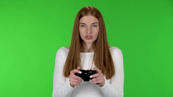 Portrait of Pretty Young Woman Is Playing a Video Game Using a Wireless Controller with Joy and Wow