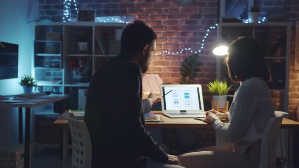 Professional Designers Discussing Smartphone Interface Using Laptop in Office