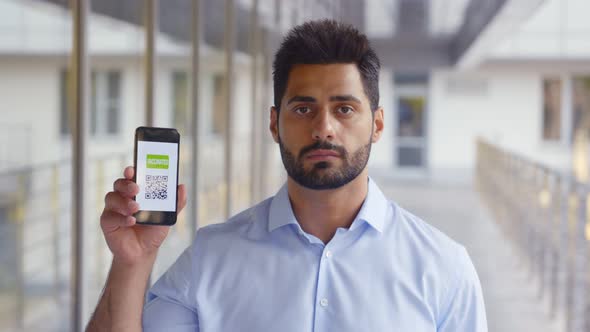 Medium Shot of Indian Young Man Showing Qrcode and Covid19 Passport on Cellphone