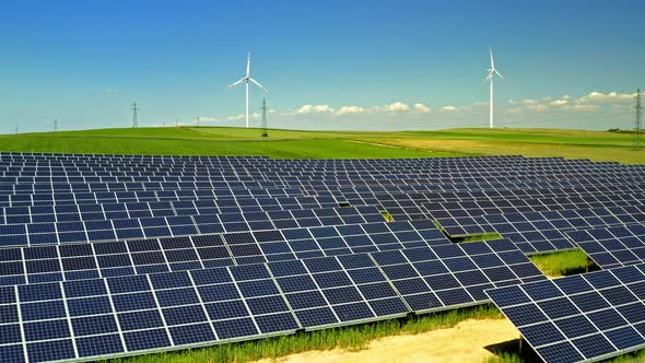 Solar Panels and wind turbines on green field with blue sky, aerial view, Poland