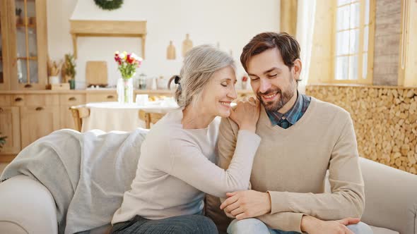 Indoors Portrait of Happy Loving Senior Greyhaired Mother and Her Adult Son Bonding Smiling to