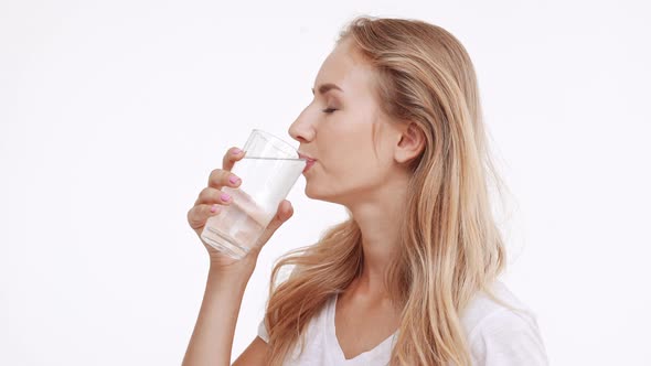 Young Beautiful Caucasian Blonde Girl Drinking Water From Glass and Smiling at Camera