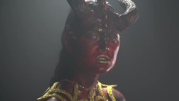 Female demon with big horns on her head and scary red eyes, close up