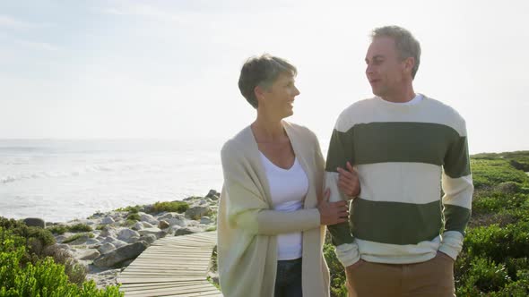 Caucasian couple enjoying free time by sea on sunny day walking path