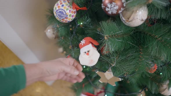 Female Hand Fixing Up Santa Claus Ornament On A Christmas Tree