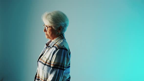 Senior European Woman with White Hair and Glasses Standing Sideways and Thinking About a Disease She