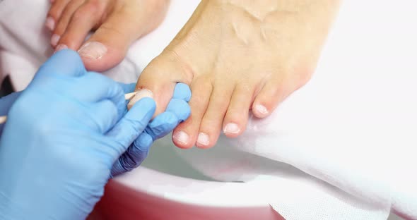 Pedicure Master Cleans Nails From Dry Skin and Dirt on Toes with Wooden Stick