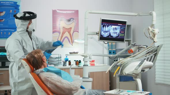 Dentist with Face Shield Reviewing Panoramic Mouth Xray Image
