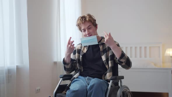 A Young Disabled Man is Putting on a Mask on His Face