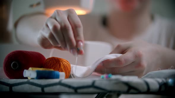 Young Woman Putting Pins in the White Cloth Before Sewing