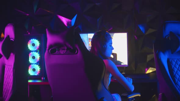 Young Pretty Woman Sitting in Neon Gaming Club and Playing Games - Turns Away From the Monitor