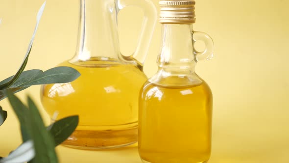 Bottle of Olive Oil and Olive Leaves on Yellow