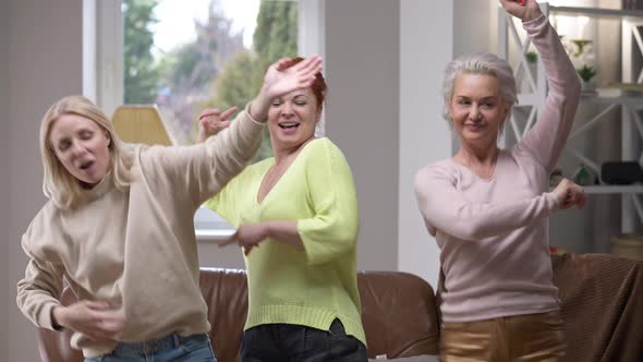 Happy Dance of Joyful Adult Women Gathering in Living Room Indoors on Weekend