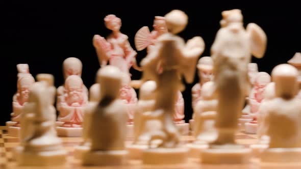 Close up Ivory chess pieces spinning on chessboard. Black background