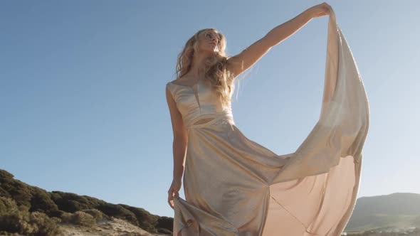 Blond Woman Dancing On Beach Under Blue Sky