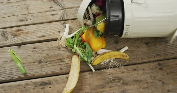 Video of white compost bin with organic waste lying on grey wooden background