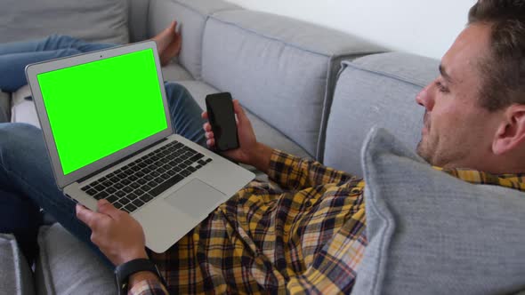 Young man using laptop in living room at home 4k