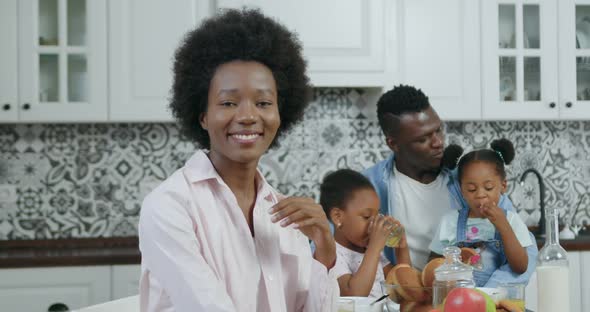 Woman with African Hairstyle Poses on Camera in Modern Kitchen Near his Husband